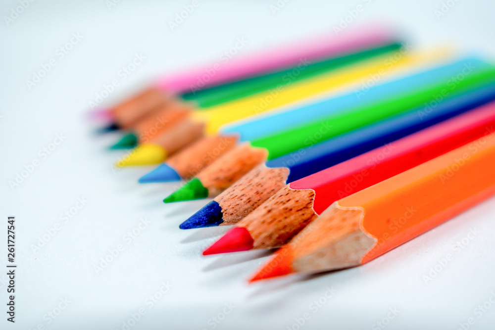 Standing Out From The Crowd Concept. Bunch of assorted multi colored pencils crayons in rainbow arrangement on white background, flat lay. Geometry pattern art design. Selective focus, blur image. Standing Out From The Crowd Concept. Bunch of assorted multi colored pencils crayons in rainbow arrangement on white background, flat lay. Geometry pattern art design. Selective focus, blur image.