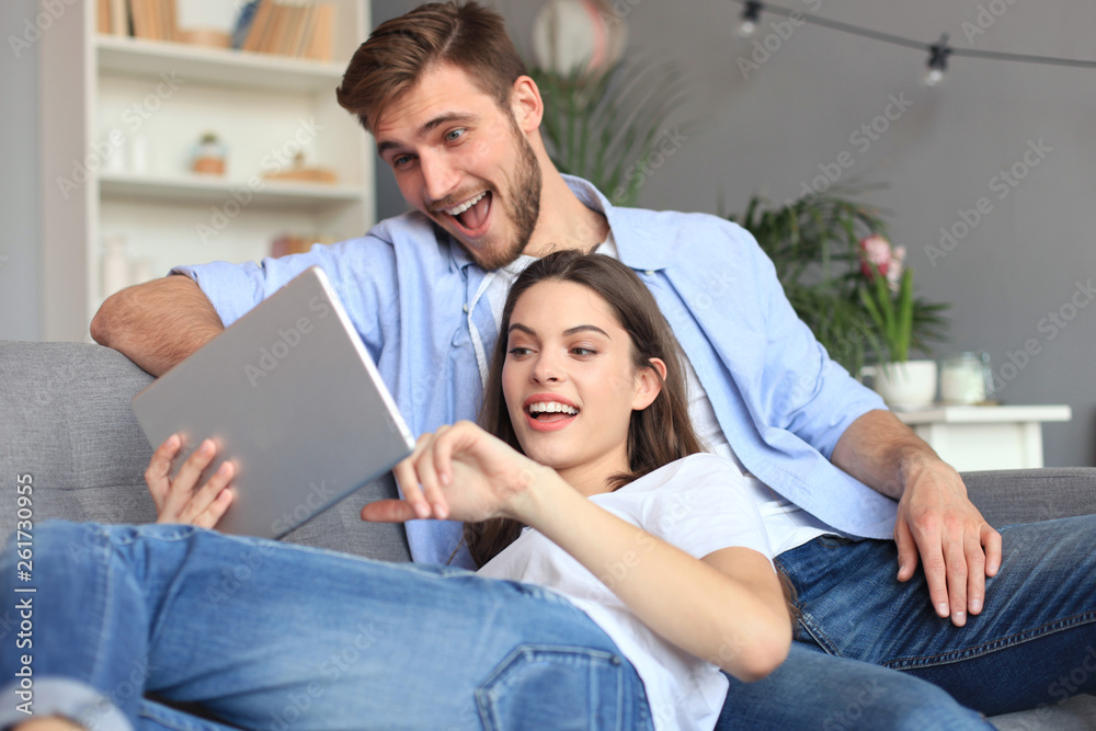 Young couple watching media content online in a tablet sitting on a sofa in the living room. Young couple watching media content online in a tablet sitting on a sofa in the living room.