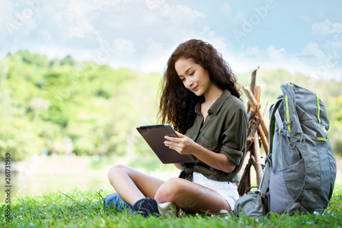 Teenage Woman travelers are sitting on tablet to shop online that involves hiking equipment. And order other items such as food, water, medicine. Summer vacations making you feel relaxed, happy © Rapeepat