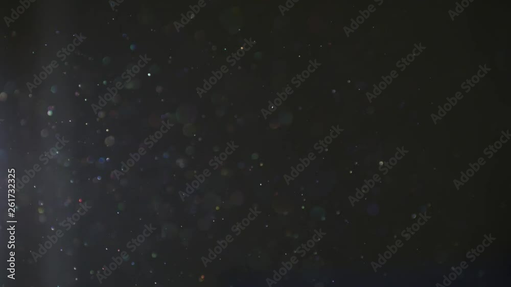 Shimmering magical dust moving through sunlit air inside a dark room creating rainbow color effects