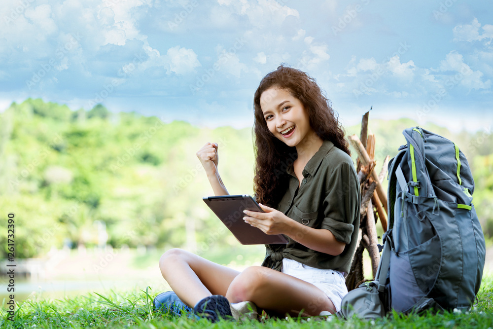 Teenage Woman travelers are sitting on tablet to shop online that involves hiking equipment. And order other items such as food, water, medicine. Summer vacations making you feel relaxed, happy Teenage Woman travelers are sitting on tablet to shop online that involves hiking equipment. And order other items such as food, water, medicine. Summer vacations making you feel relaxed, happy