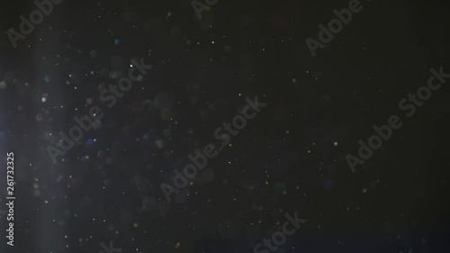 Shimmering magical dust moving through sunlit air inside a dark room creating rainbow color effects