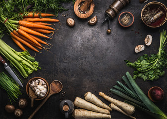 Food background with various organic farm vegetables on dark rustic table with kitchen utensils, herbs and spices, top view. Frame. Copy space. Vegan and vegetarian food concept. Healthy lifestyle