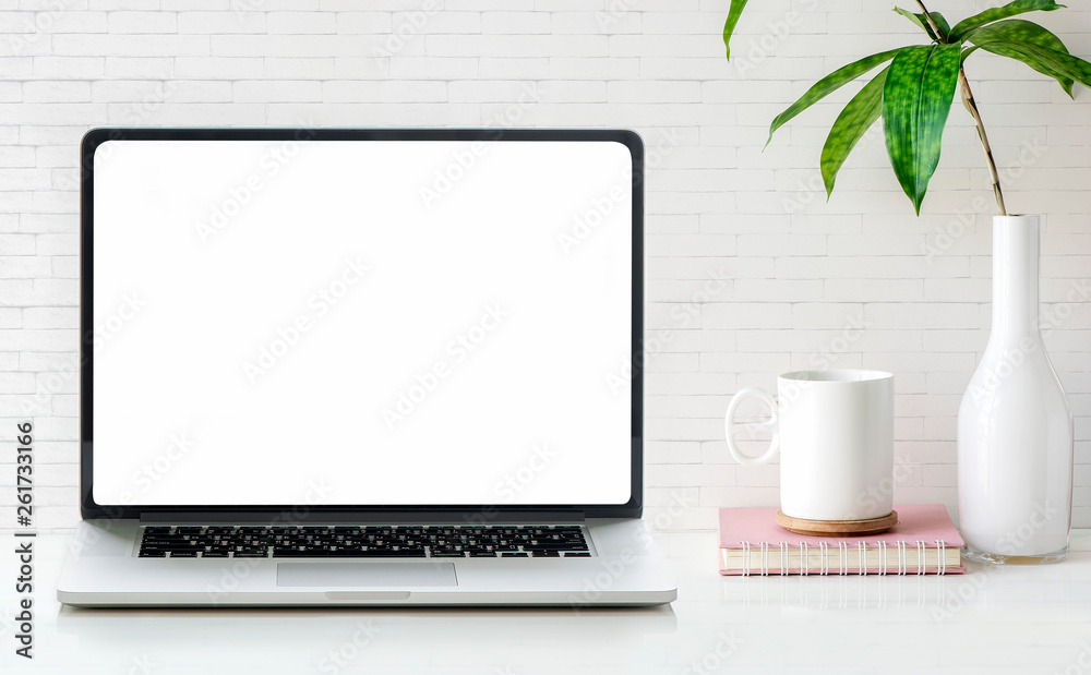 Fototapeta premium Mockup blank screen laptop with cup, book and houseplant on white table and brick wall.