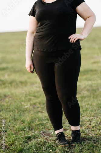 Cropped image of female overweight obese body. Fat woman in sportswear standing outdoors. Weight loss concept