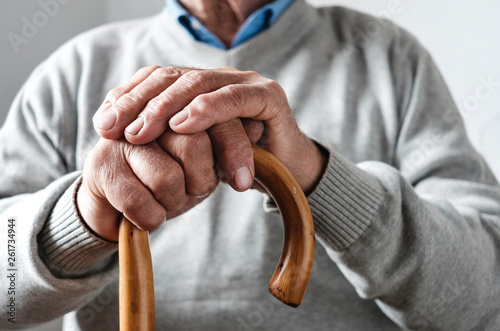 Hands of an elderly man resting on a walking cane photo