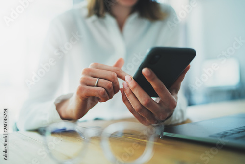 Female hands holding smartphone and touching screen.Businesswoman using mobile phone.Closeup on blurred background