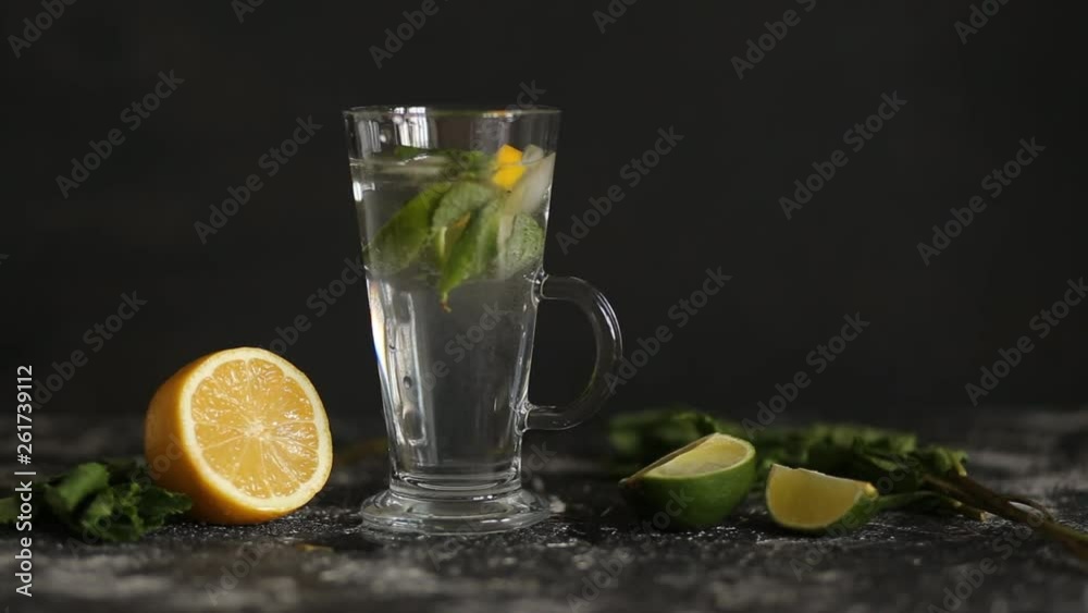 Mojito cocktail with mint and lime on black background. Summer, refreshing drinks. Soda water bubbles splashing, floating drop in transparent glass cup
