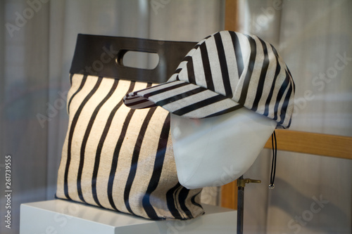 Bag and baseball cap with stripes on the shop window behind the glass.
