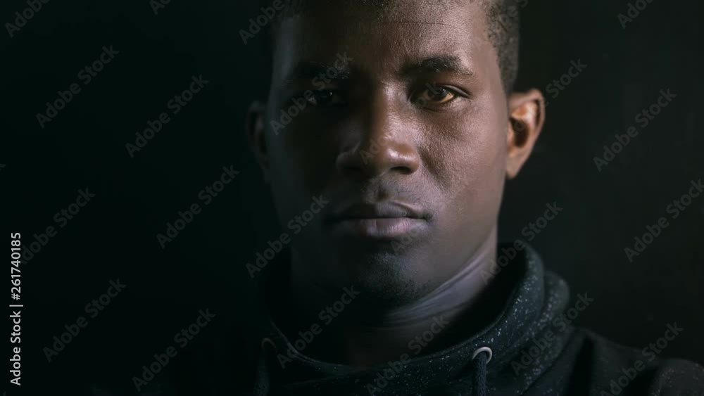 Serious confident young american african man staring at camera in the dark Serious confident young american african man staring at camera in the dark