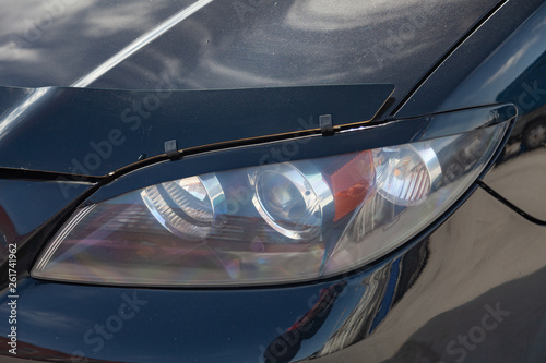 Black car front headlight view with dark gray interior in excellent condition in a parking space among other cars