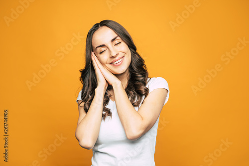 To have a dream. Sweet girl with slightly curled hair, tender smile and naturally glowing skin is having her pleasant dreams.