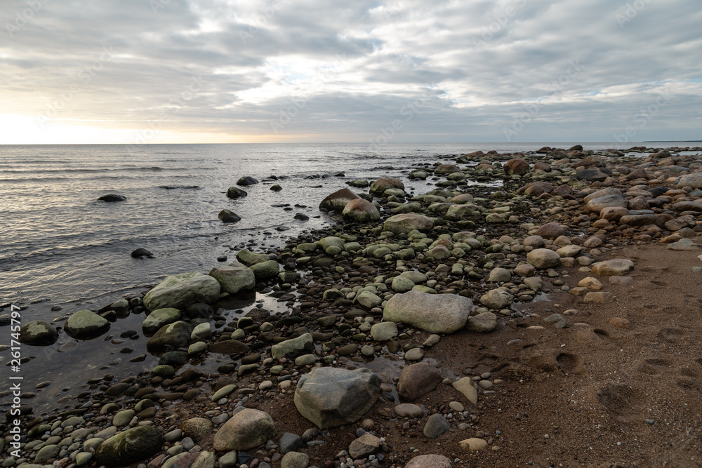 Boulder beach during a cloudy sunset with green seaweed covered rocks - Veczemju Klintis, Latvia - April 13, 2019 Boulder beach during a cloudy sunset with green seaweed covered rocks - Veczemju Klintis, Latvia - April 13, 2019