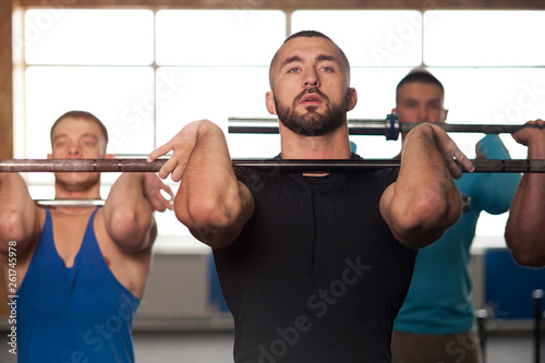 Young People in Gym Training With Barbells
