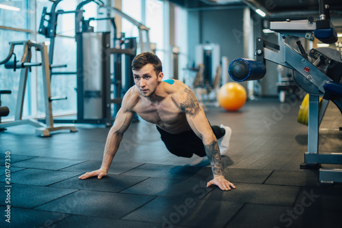 Man with naked torso wrung out from floor in gym