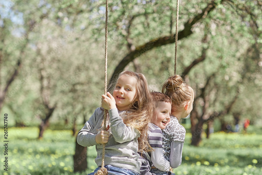 three little friends sitting on a swing in the garden on a spring day. three little friends sitting on a swing in the garden on a spring day.