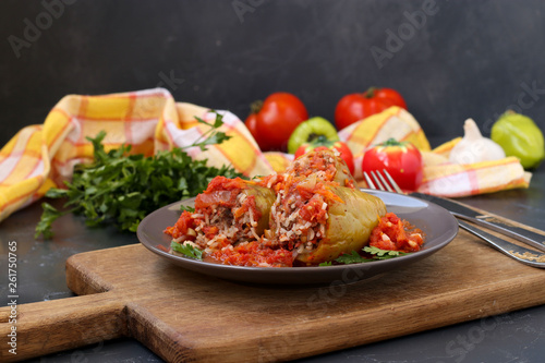 Stuffed peppers with meat  rice and tomato sauce located on a dark background