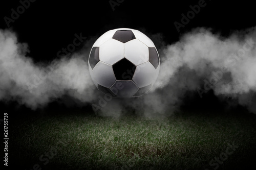 Traditional soccer ball on soccer field. Close up view of soccer ball (football) on green grass with dark toned foggy background