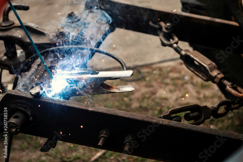 Close up industrial worker is welding repair auto in factory. Mechanical engineering, agricultural technology, garage concept.