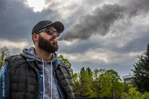 man with a beard smokes an electronic cigarette