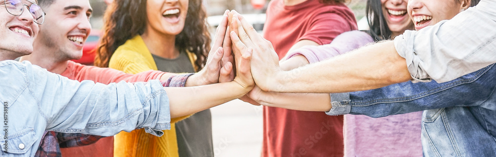 Group of diverse friends stacking hands outdoor - Happy young people having fun joining and celebrating together - Millennials, friendship, empowering, partnership and youth lifestyle concept - obrazy, fototapety, plakaty 