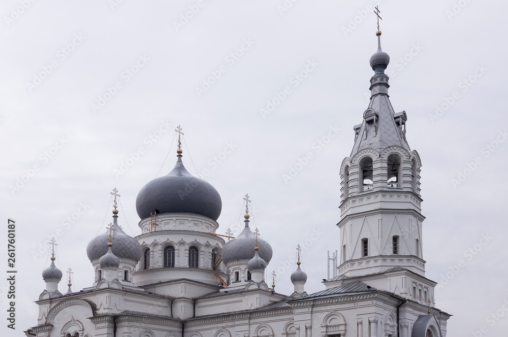 Obraz premium Christian orthodox white church with silver and grey domes with gold crosses. Calm grey sky above