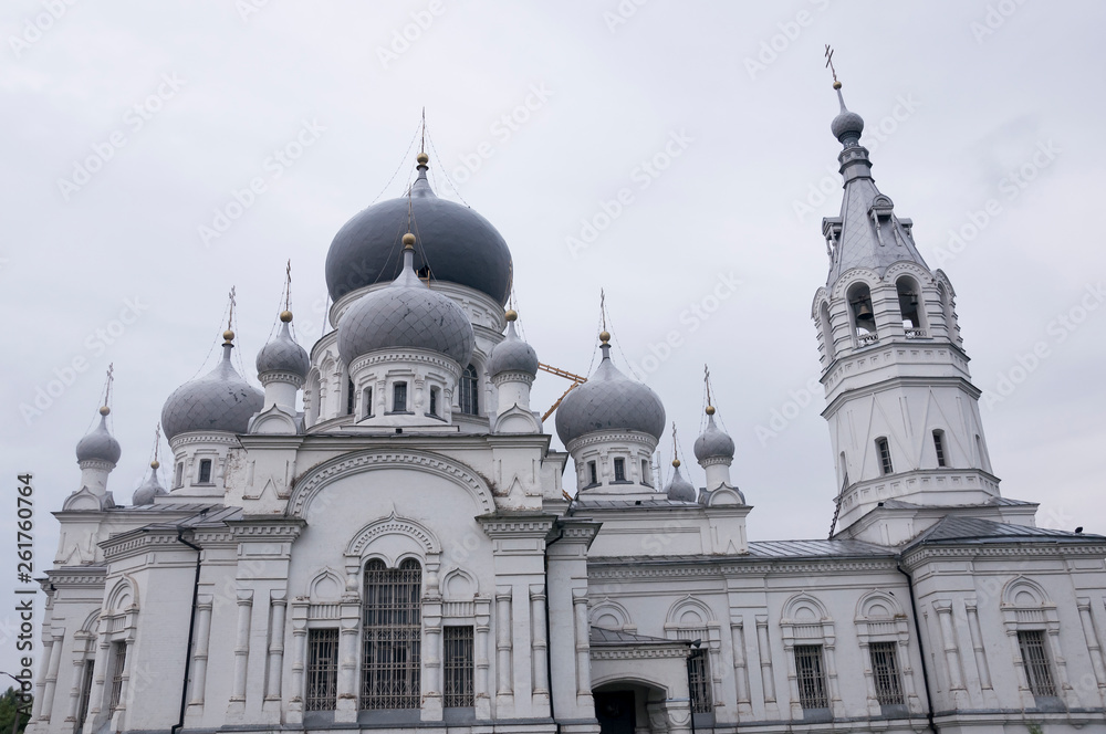Naklejka premium Christian orthodox white church with silver and grey domes with gold crosses. Calm grey sky above
