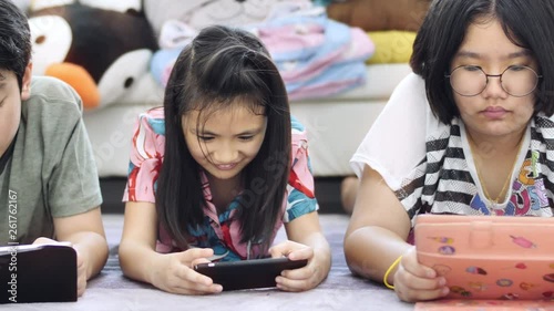 Child playing tablet or smartphone at home , Asian boy and girl playing game on mobile phone together with smile face.
