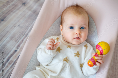 Adorable baby girl having fun in bouncer. Toddler playing with colorful rattle toy. Activities for infants