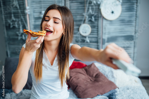 Smiling woman holding console and eating tasty pizza! photo