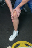 Sportsman in the white sneakers having pain in leg after exercise. close up. focus is on leg..