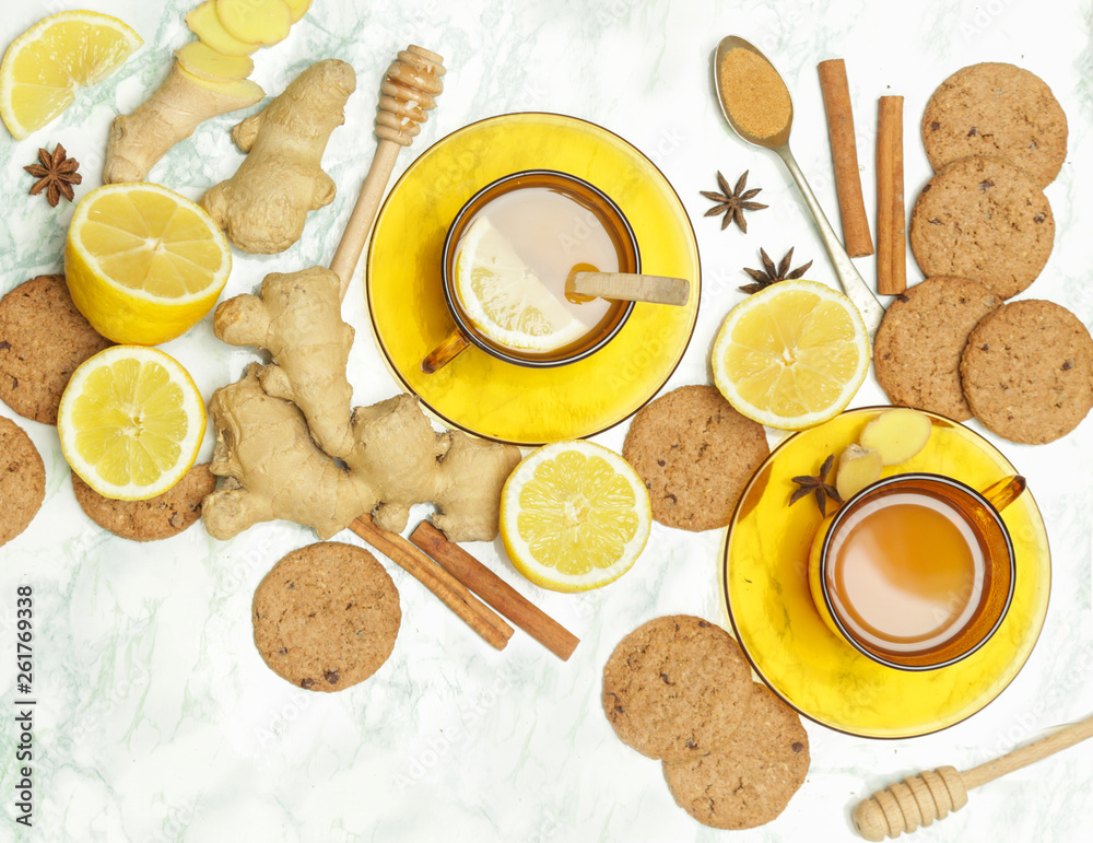 Ginger tea in a cup with ginger roots and lemon on marble textured background, top view. A healthy lifestyle, anti-flu and anti-inflammatory concept. Ginger tea in a cup with ginger roots and lemon on marble textured background, top view. A healthy lifestyle, anti-flu and anti-inflammatory concept.