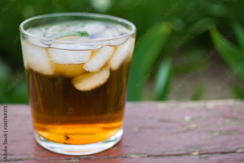 Glass of ice tea on wooden with nature background - Glass of ice tea on wooden with nature background -