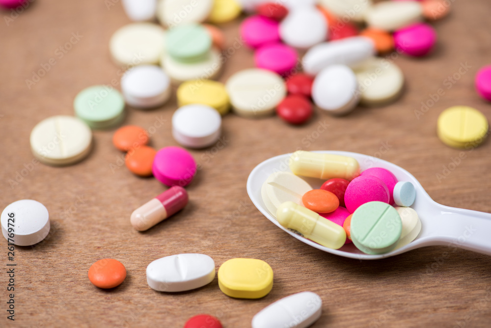 pills in white spoon with wood background