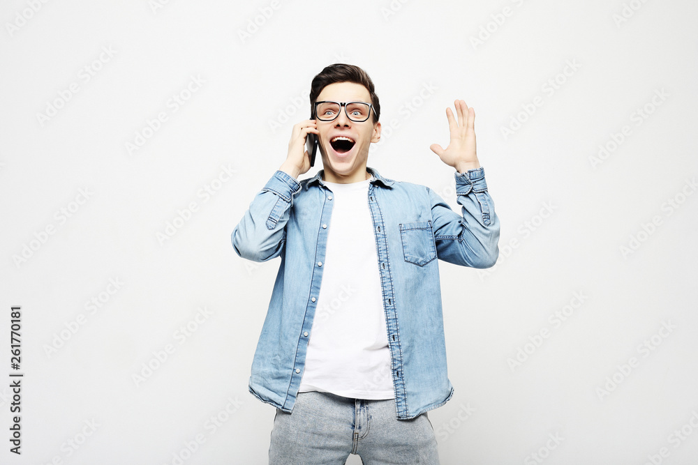 Smiling man in t-shirt talking by smartphone over grey background Smiling man in t-shirt talking by smartphone over grey background