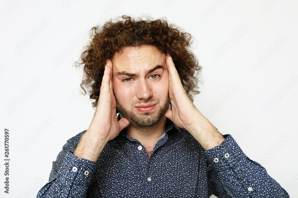 Close up of frustrated young man with head in hand against white background