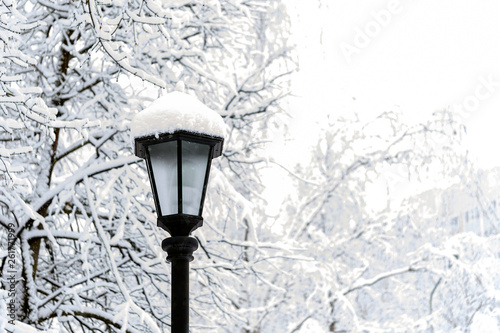 Winter street and city lantern under white snow. Lantern in the snow in the winter in the park. Snowfall in winter.