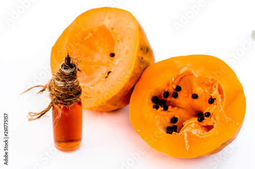 Raw cut papaya isolated on white along with its concentration or essence in a transparent glass bottle. photo