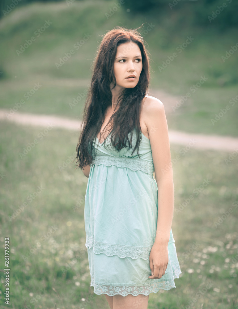thoughtful young woman with long hair standing in a meadow thoughtful young woman with long hair standing in a meadow