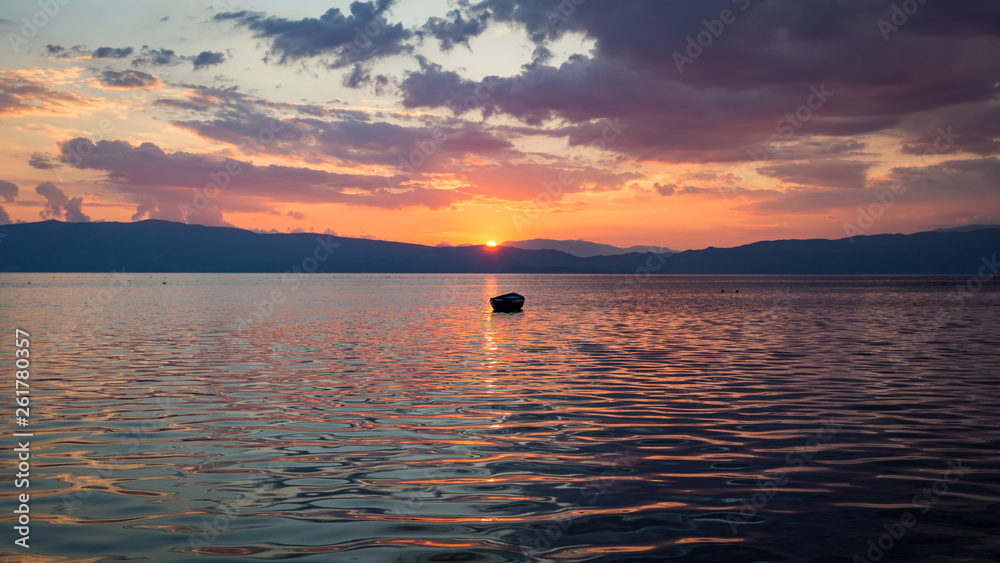 Fototapeta premium Sunset over Ohrid's lake, North Macedonia, Europe, with boat and cloudy sky