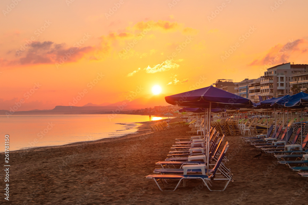 Morning on the beach near the sea. Sun chairs on sandy beach at sunrise, Crete, Rethymno. Beautifull sunrise on the beach line.