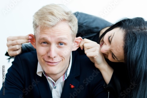 Girl pulling boyfriend's ears to make a fun.