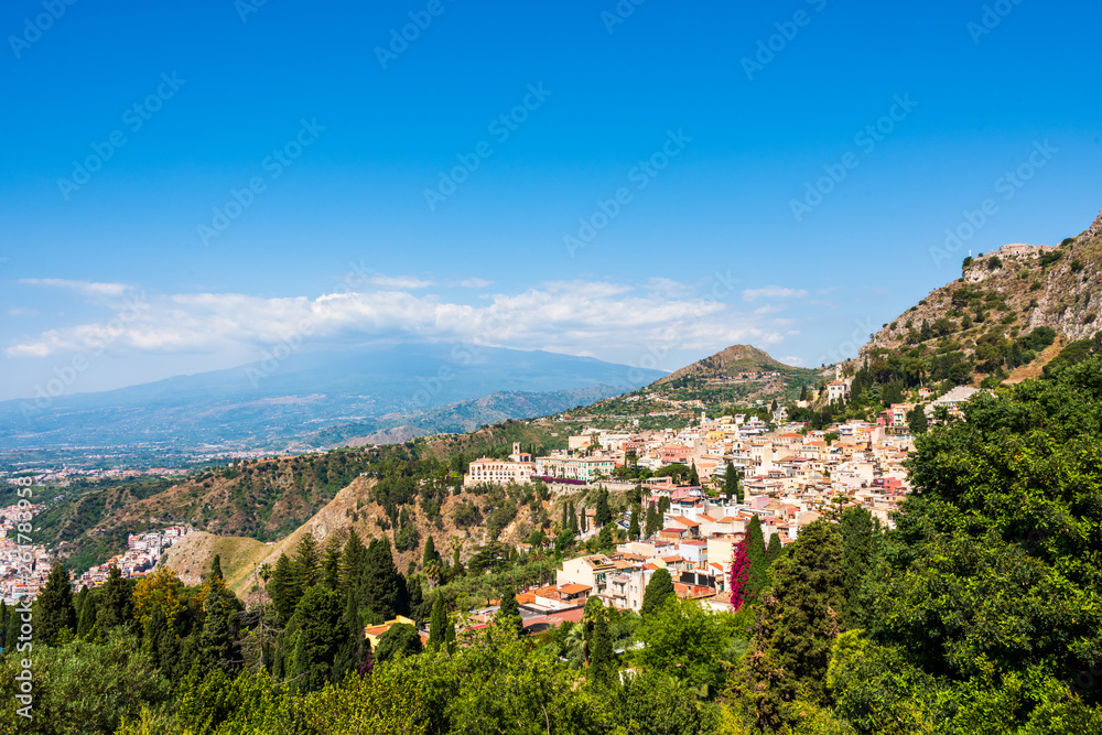 Fototapeta premium Stadtansicht von Taormina in Sizilien mit dem wolkenverhangenen Vulkan Ätna