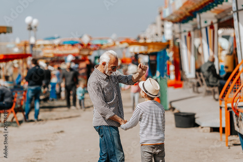 Grandfather and grandson having fun and spending good quality time together in amusement park. © Dusko