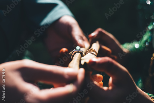 Married couple with traditional wedding dress showing their wedding rings in a dark lighting.selective focus
