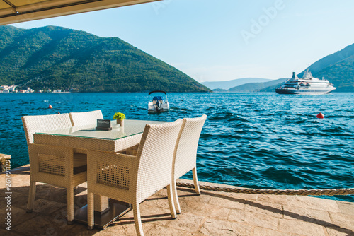 cafe table on beach with beautiful view of sea and mountains. reserved plate on it