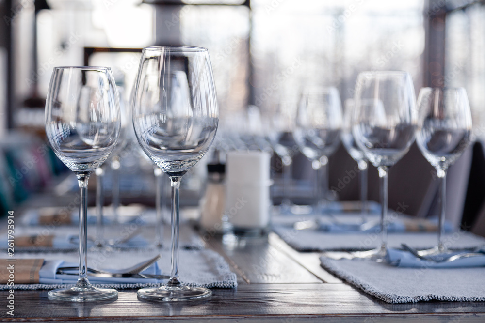 Restaurant interior, modern setting, wine and water glasses, forks and knives on textile napkins stand in row on vintage wooden table. Concept banquet, birthday, conference, group lunch Restaurant interior, modern setting, wine and water glasses, forks and knives on textile napkins stand in row on vintage wooden table. Concept banquet, birthday, conference, group lunch