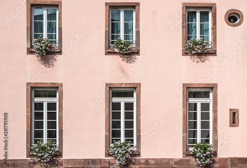 Pink facade of a building with windows and flowers in pots in the historic district "Petite France" in Strasbourg, France