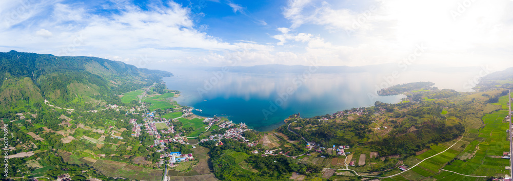 Naklejka premium Aerial: lake Toba and Samosir Island view from above Sumatra Indonesia. Huge volcanic caldera covered by water, traditional Batak villages, green rice paddies, equatorial forest.