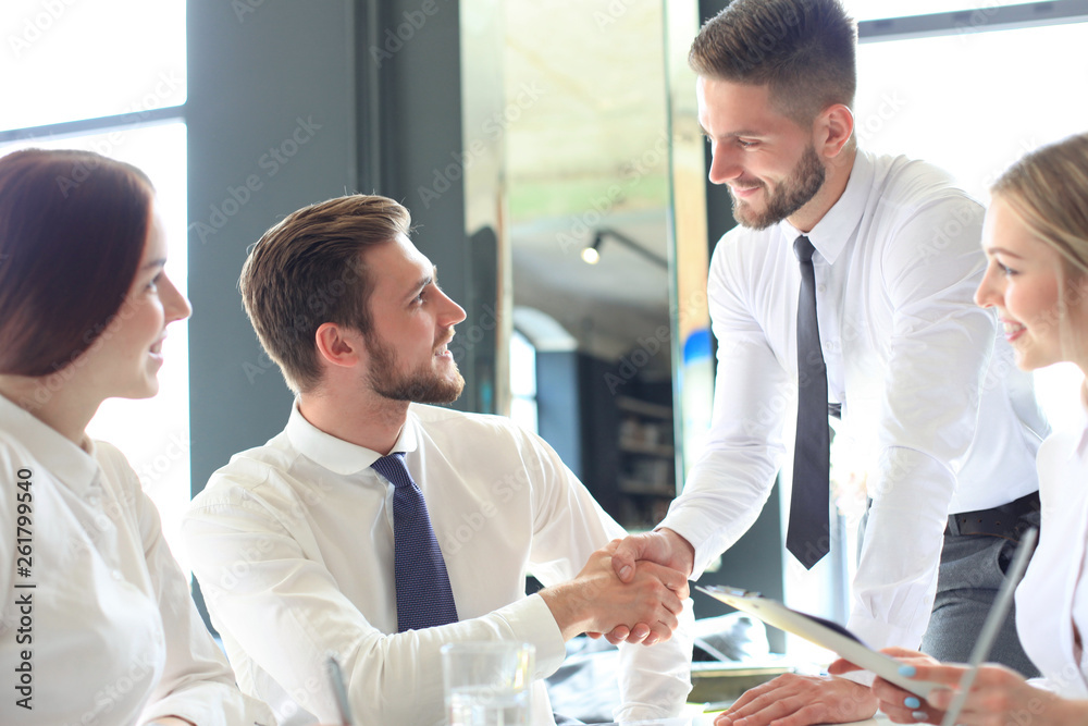Businessman shaking hands to seal a deal with his partner and colleagues in office. Businessman shaking hands to seal a deal with his partner and colleagues in office.